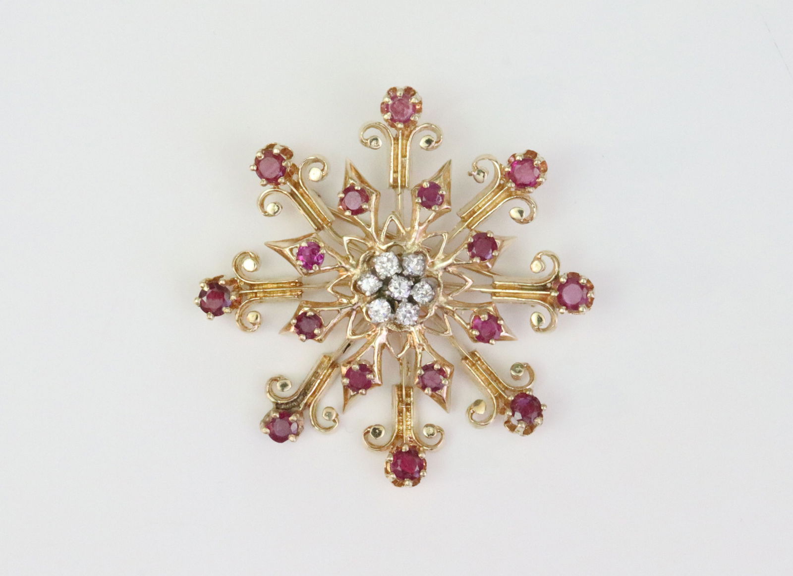 14K RUBY & DIAMOND STARBURST PIN: set with 16 round rubies approx. 2.00ctw, and 7 round diamonds approx. 0.35ctw, diameter 1.75in., in yellow gold, tests 14K, 13.7gms., Opening Bid $900