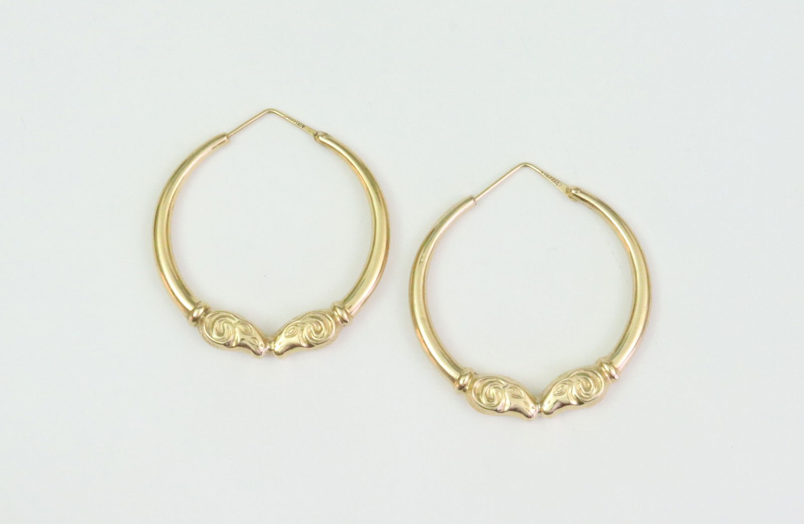 PAIR 18K HOLLOW GOLD RAMS HEAD HOOPS: stamped 'Italy 18K', one hoop with 2 scant dents, 1.75in., gross weight 10gms., Opening Bid $700
