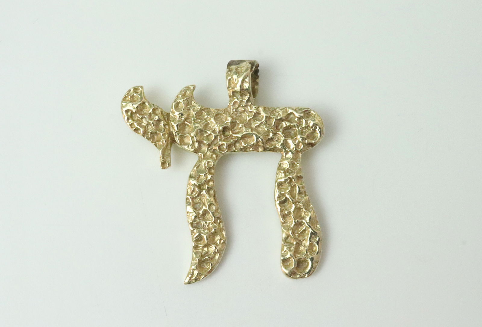 14K JUDAICA CHAI PENDANT: in brutalist design, 1.4x1.5in., in yellow gold, stamped 14K, 14.2gms., Opening Bid $700