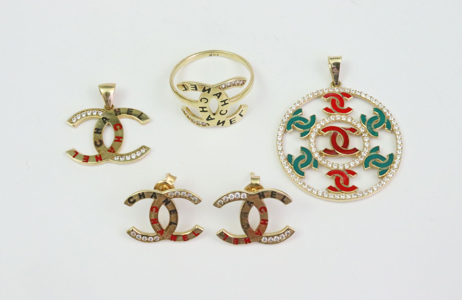 (4) PIECE 18K CHANEL REPLICA JEWELRY GROUP: in assorted enamels, includes a 27mm pendant with white gemstone borders, a 19mm CC logo pendant with matching 12mm stud earrings, all with white gemstone accents, and a size 6.5 double CC ring,