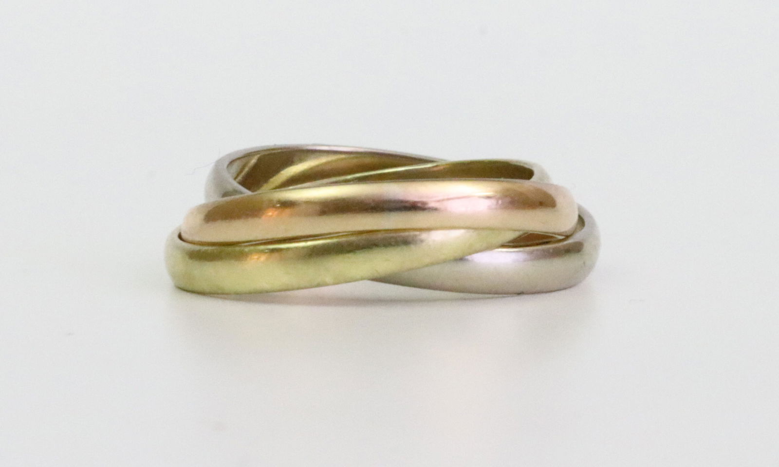 1970'S CARTIER 18K TRINITY RING: comprising 3 intertwined moving rings in yellow, white, and rose gold, stamped faintly ('Cartier') '18K', and with personal inscriptions, one dated 77, approx. size 6, 5.4gms., Opening Bid $600