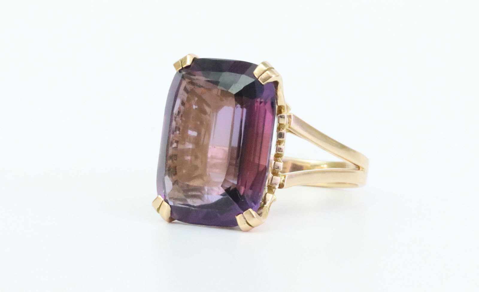 18K VINTAGE AMETHYST COCKTAIL RING: set with an emerald cut amethyst stone approx. 11.6ct (17.8x13.5x7.3mm), in yellow gold reticulated setting, tests 18K, and with diamond or eagle hallmark on the shank exterior, size 5.75, 8.6gms.,