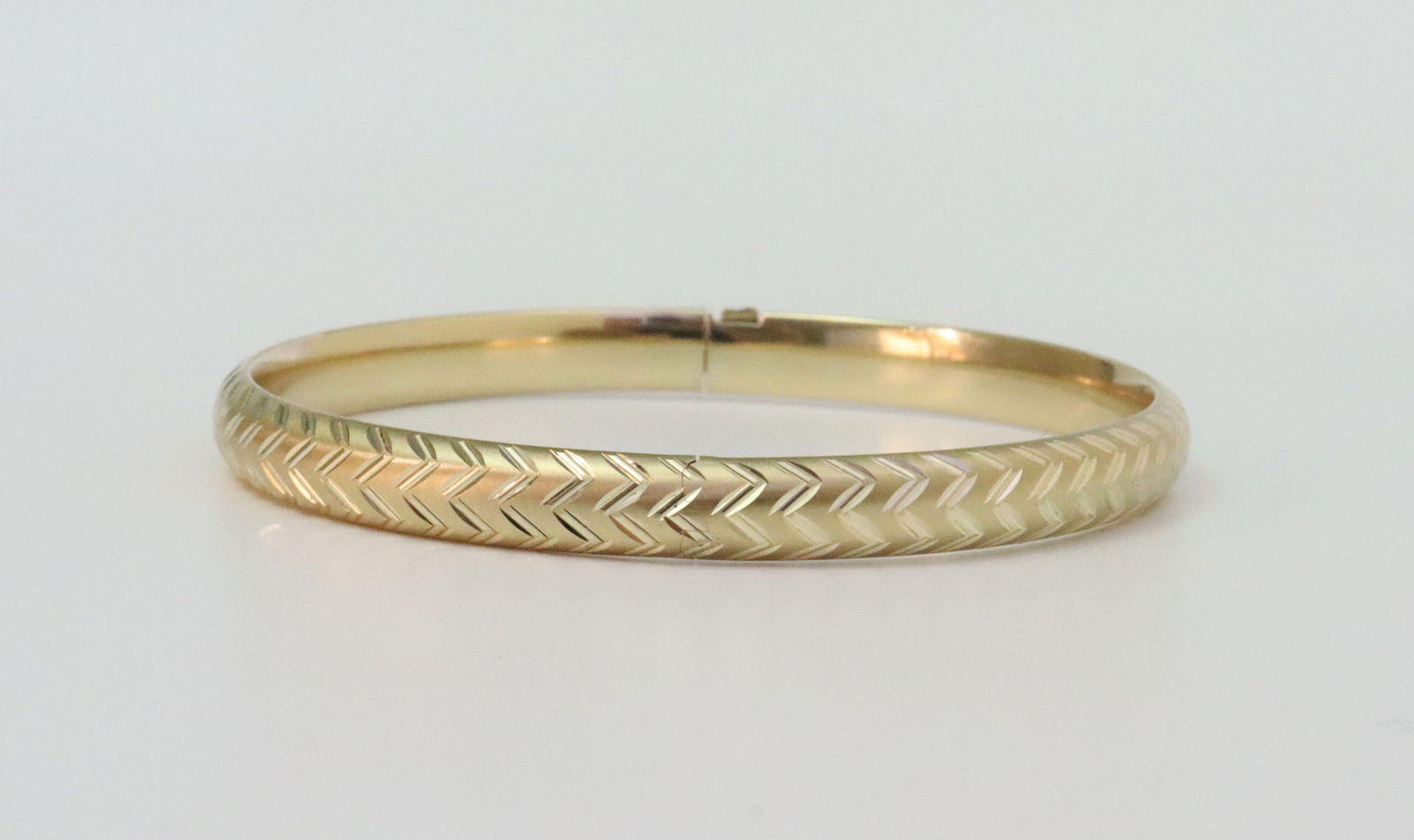 14K SLIDE HINGED BANGLE BRACELET: in yellow gold with diamond-cut design, stamped 14K, width 6mm, inner circumference 7in., 7.4gms., Opening Bid $400