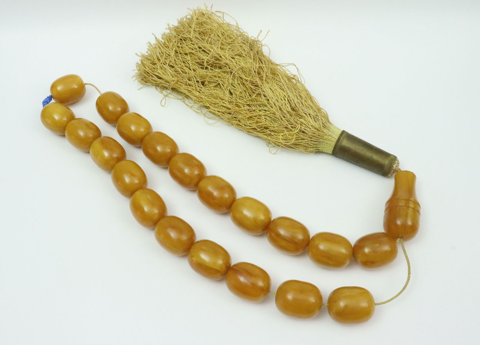 LARGE BUTTERSCOTCH AMBER BEADED NECKLACE: comprising 20 large (27x33mm) amber beads strung on cord, suspending a (61x27mm) amber pendant bead surmounting a large metal-mounted tassel, overall good condition, some exposed string, pendant with