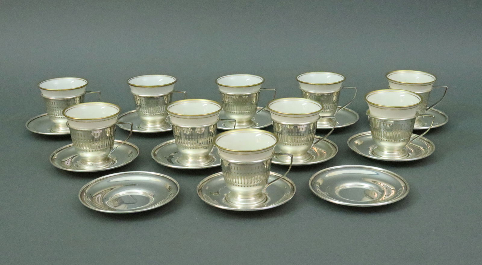 (22) PIECE STERLING DEMITASSE SET: comprised of 12 saucers and 10 pierced cup holders marked Sterling, and 10 liners (6 Lenox in cream and 4 Buffalo China in white), monogrammed, cup holder with liner 2in., 9.2ozt., Opening Bid $400