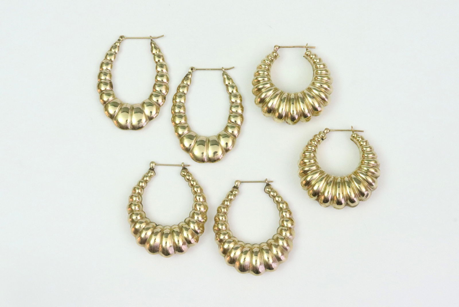 (3) PAIRS 14K HOLLOW GOLD HOOPS: in ribbed hammered design, thickest pair with a few gold fissures at underside seams (one moderate, see image), small dent, one earring with minor solder remnant at closure catch, all stamped