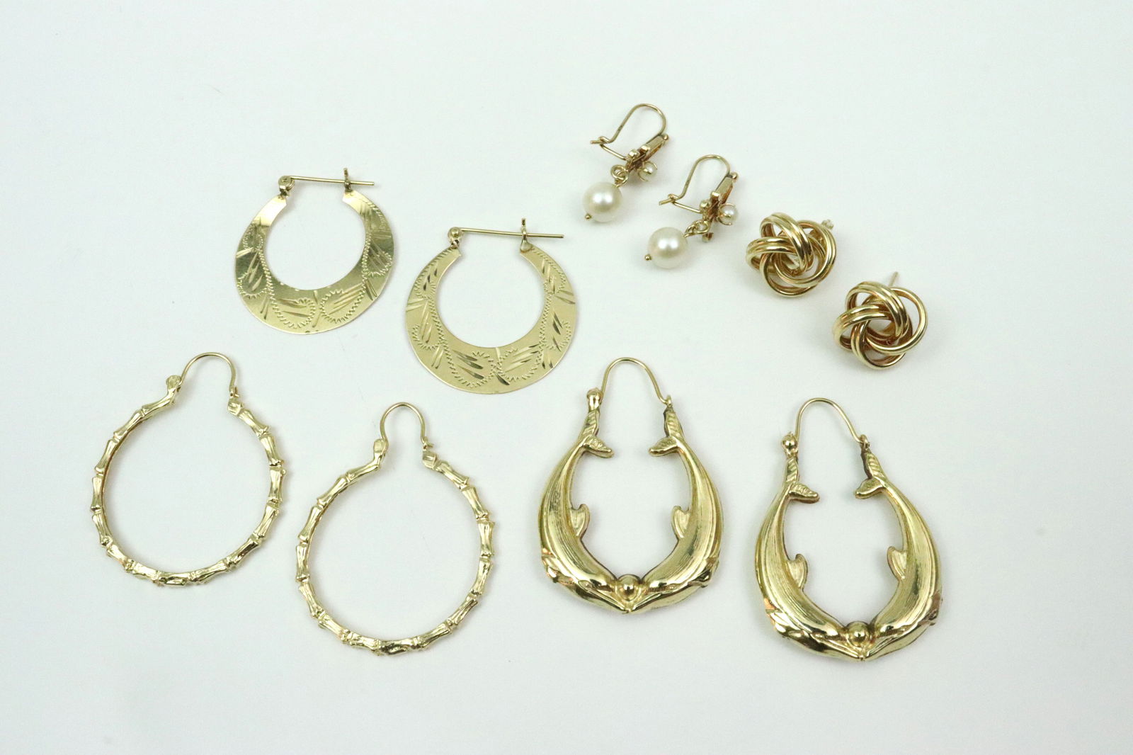 (5) PAIRS 14K EARRINGS: including dolphin hoops, bamboo form hoops (one with bend), bright cut hoops (some bending, some solder remnants at closure attachments), a pair of (14mm) love knot studs (one earring back missing), a