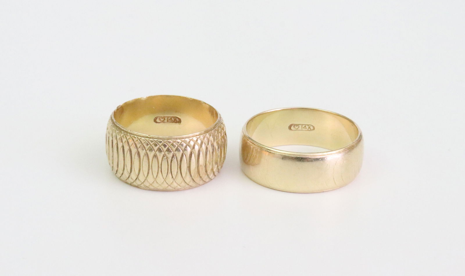 (2) WEDDING BANDS: including a ladies wide band in diamond-cut lattice motif, edge roughness and dings, size approx. 6.5, and a gent's band, once of same pattern, but well-worn, size approx. 8.75, each stamped 14K,