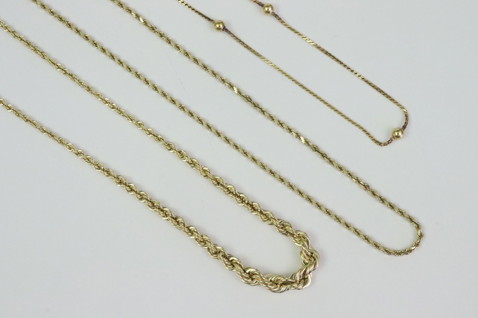(3) GOLD NECKCHAINS: including a 17" Italian 18K serpentine chain with gold ball stations, stamped 750, and with Italian hallmark 264 AR (Arezzo), 3.7gms., a 20" 14K rope chain, and a 17" 14K rope chain with graduated cen