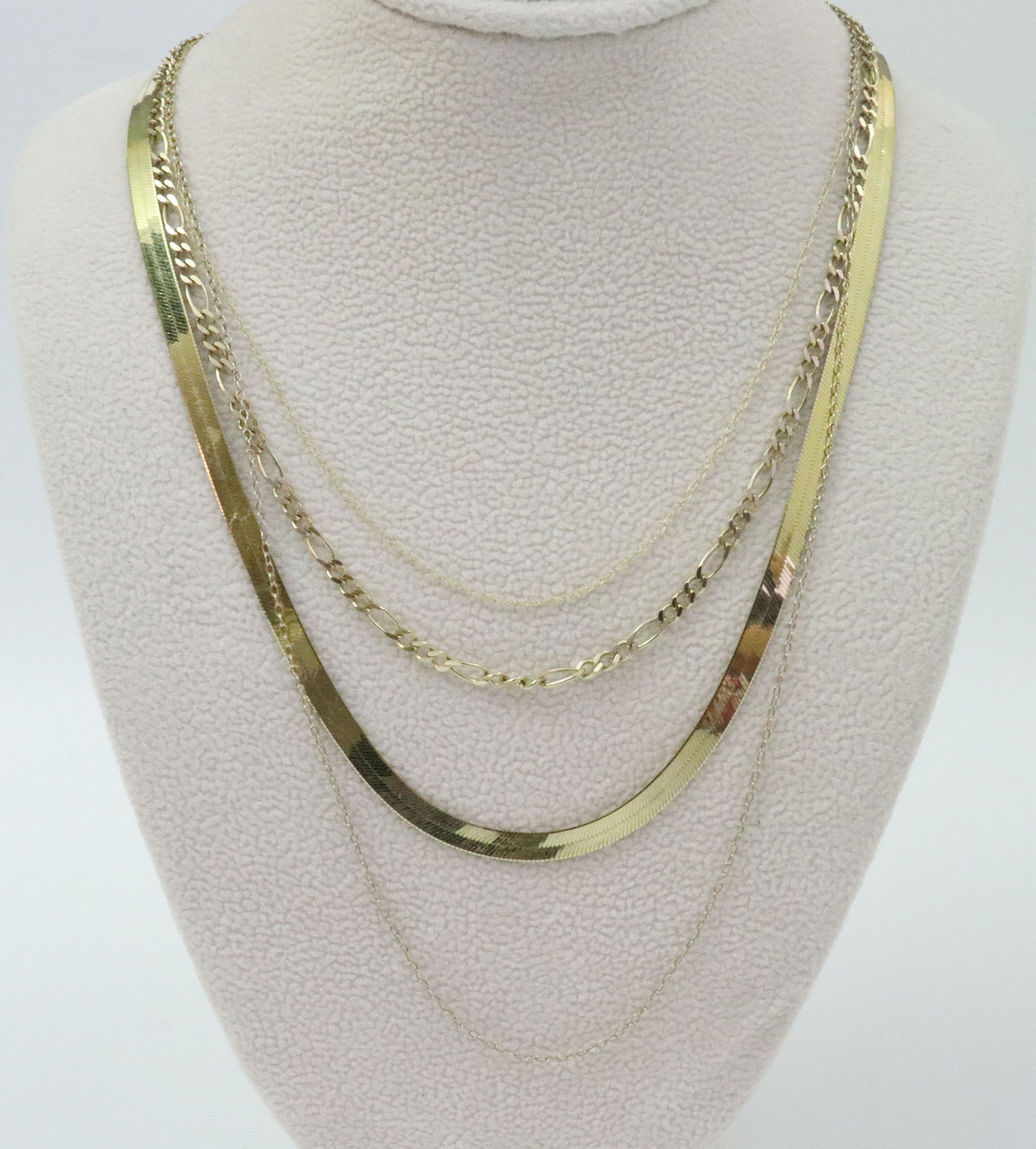 (4) GOLD NECKCHAINS: all 18in., 14K includes an Italian herringbone (a couple creases), and a white gold cable link trace chain, 6.8gms., 10K includes a figaro chain, and a parallel link trace chain, 4.7gms., all aptly