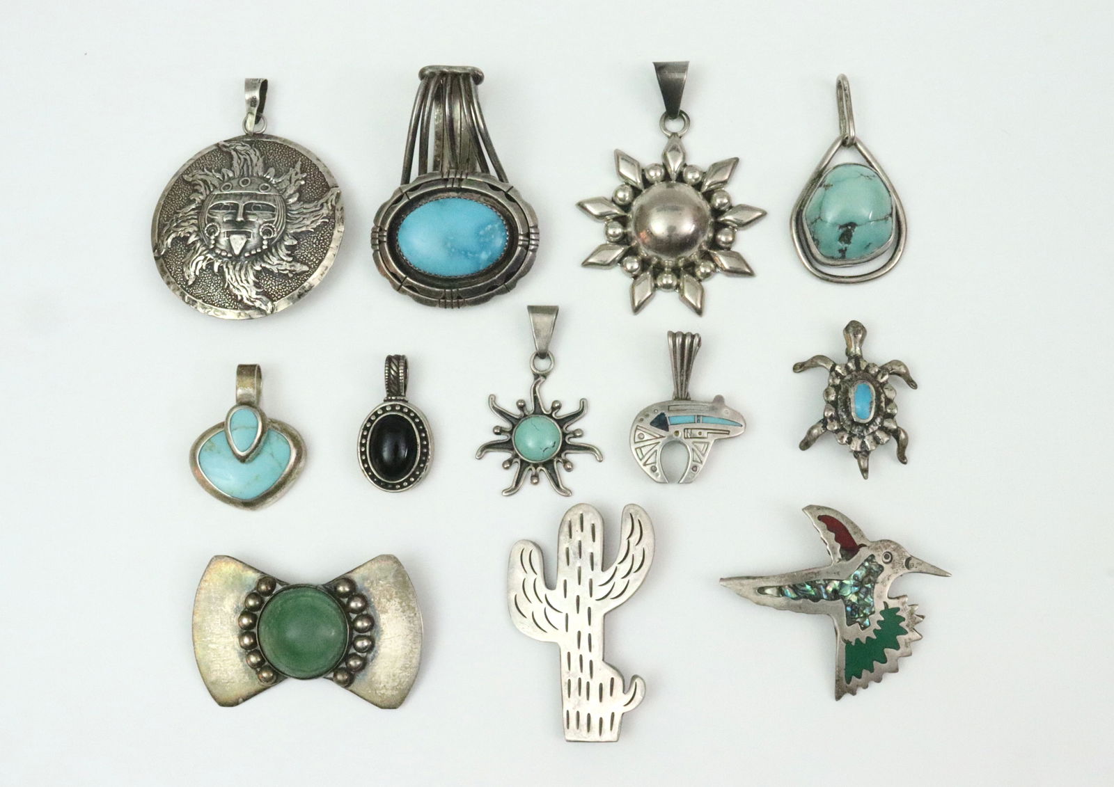 (12) MAINLY TURQUOISE PINS & PENDANTS: 8 pendants include a circular sun god, an oval turquoise pendant with large reticulated bale, a Mexican sun, a turquoise boulder pendant signed JR, a Mexican heart, an oval onyx, a sun pendant with