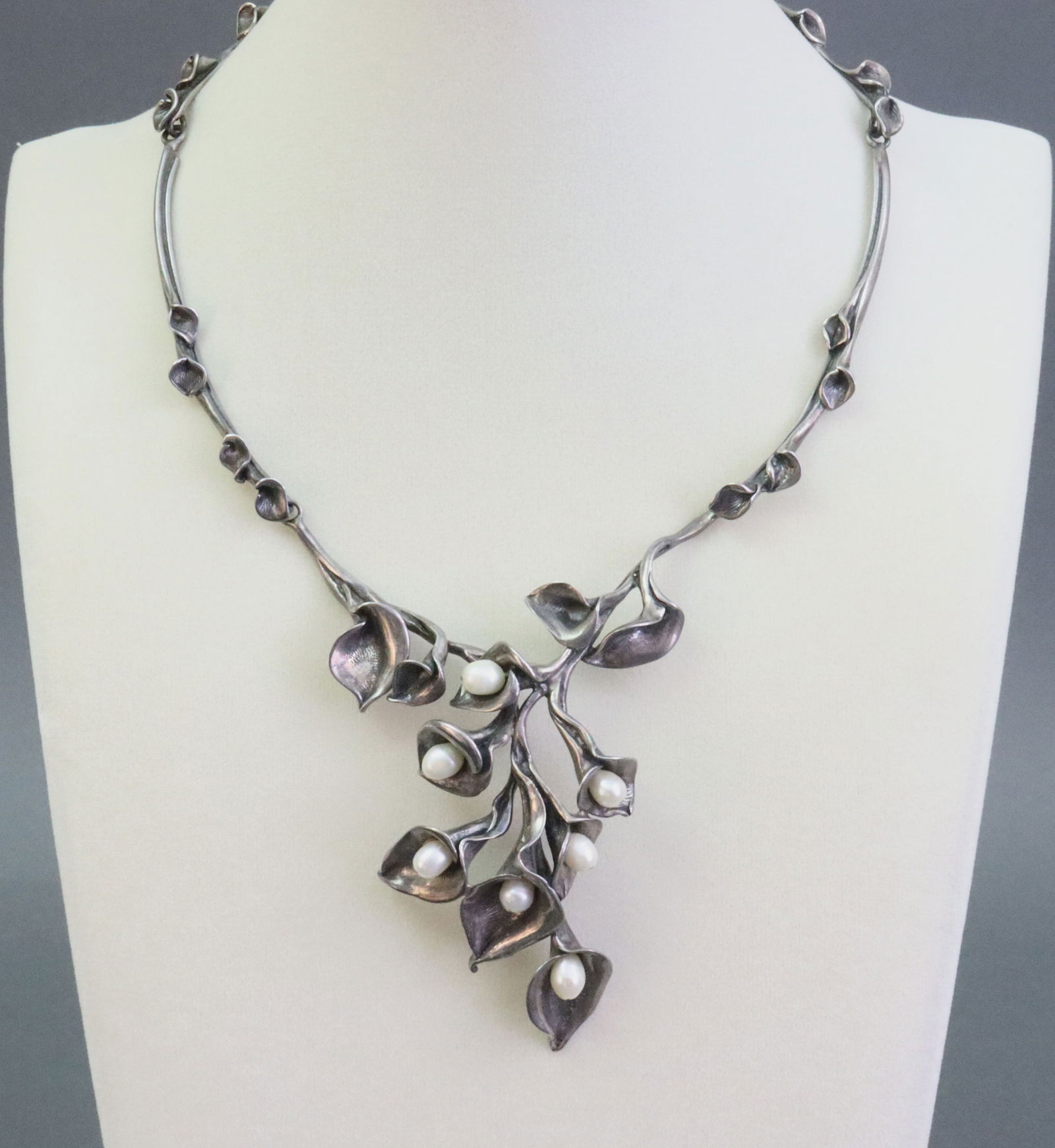 SILVER MODERNIST CALLA LILY NECKLACE WITH PEARLS: likely Greek, comprising 7 (5.5-6mm) fresh water pearls set within open calla lily flowers, articulated calla lily twig collar (lobster claw clasp appears a later addition), stamped 925, necklace