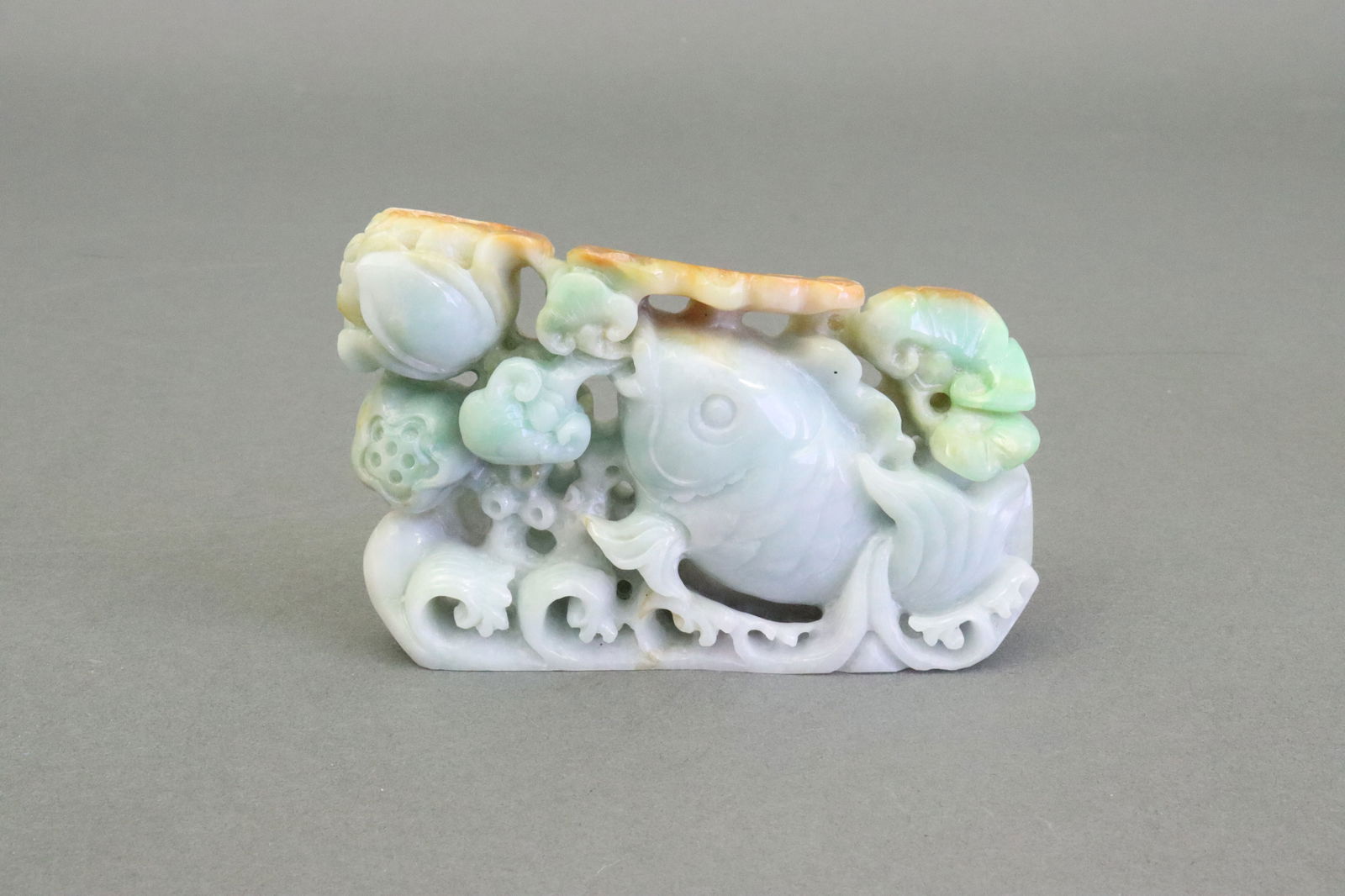 CHINESE JADEITE JADE FISH CARVING W/LOTUS & WAVES: in green with russet variation, height 2.75in., width 4.5in., Chinese storage box, Estate Collection