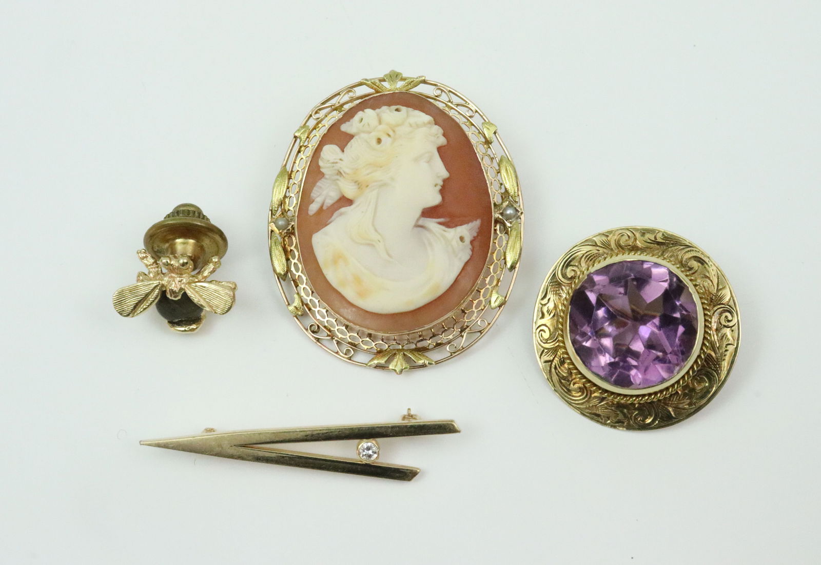(4) 14K PINS: including a filigree cameo pin pendant with hinged bale, 1.5in., 7.3gms., a geometric bar pin with accent diamond, length 1.5in., 1.3gms., a circular (11.0ct) amethyst pin with bright-cut design,