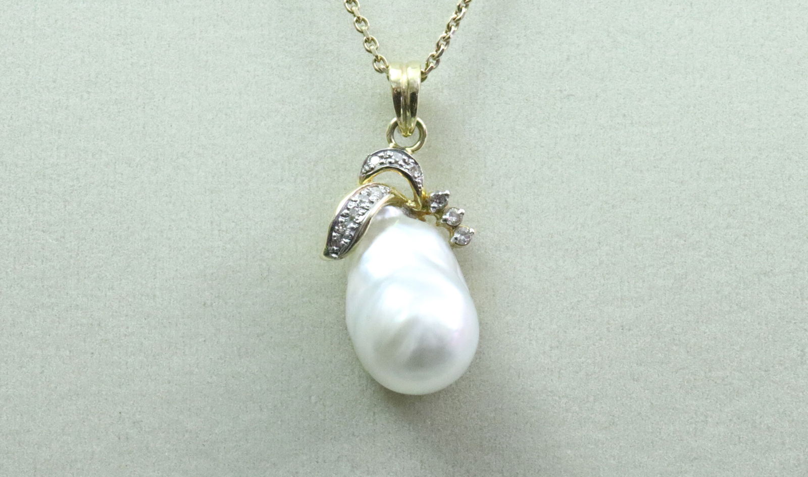 14K BAROQUE PEARL & DIAMOND PENDANT ON CHAIN: the pendant featuring an (18x12mm) baroque pearl accented with 11 round diamonds approx. 0.17ctw, in tested 14K yellow gold (old adhesive remnants to backside), overall length 1.3in., 6.6gms., on