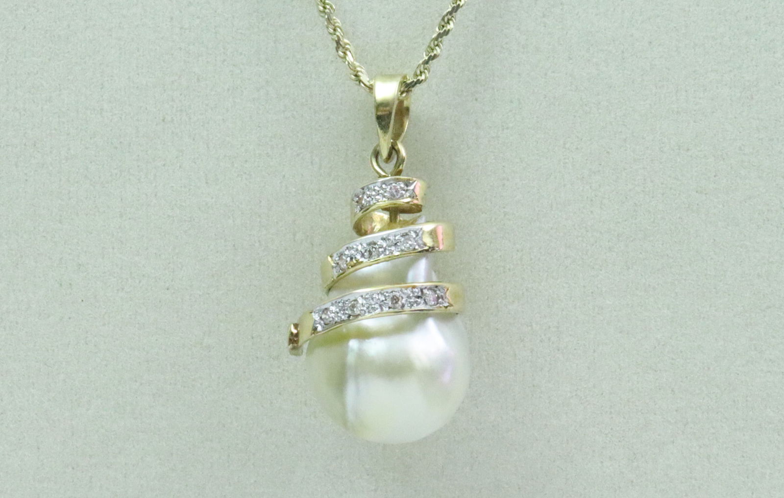 14K BAROQUE PEARL & DIAMOND PENDANT ON CHAIN: the pendant featuring a (17x13mm) baroque pearl accented with 9 round diamonds approx. 0.09ctw (pearl with some imperfections, minor adhesive remnant at point of attachment), in yellow gold, stamped