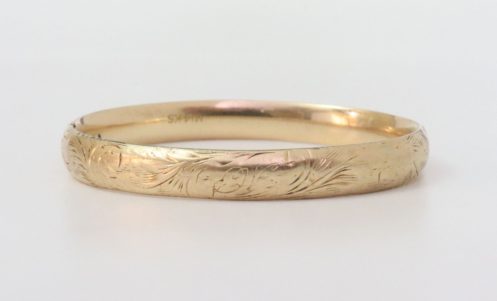 14K BABY BANGLE: slide hinged bangle with etched design (slide broken not affecting closure, dents), in yellow gold, stamped 14K, width 6mm, inner circumference 5in., 5.2gms., Opening Bid $250