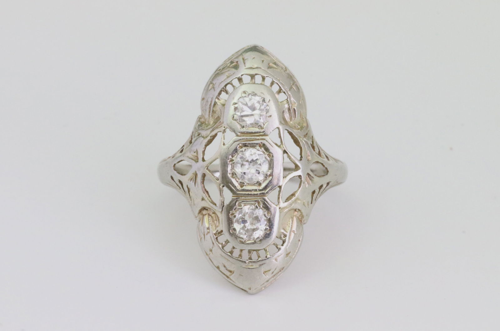 18K ART DECO DIAMOND RING: set with 3 round diamonds approx. 0.54ctw (one diamond with black pique line inclusion), overall head 24x17mm, in white filigree gold, tests 18K, size 5, 2.9gms., Opening Bid $200