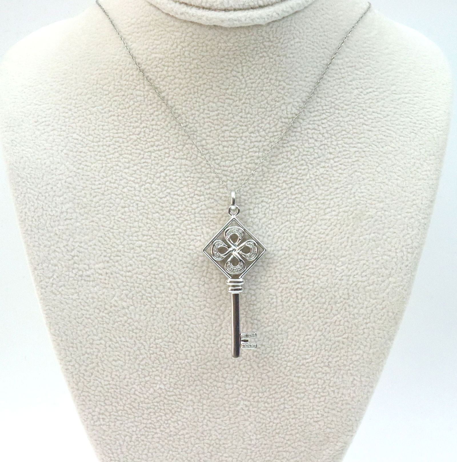 14K DIAMOND KEY PENDANT ON CHAIN: comprising a 1.5" key form pendant accented with 28 melee diamonds, on 19" parallel link trace chain, each in white gold stamped 14K, 4.9gms.