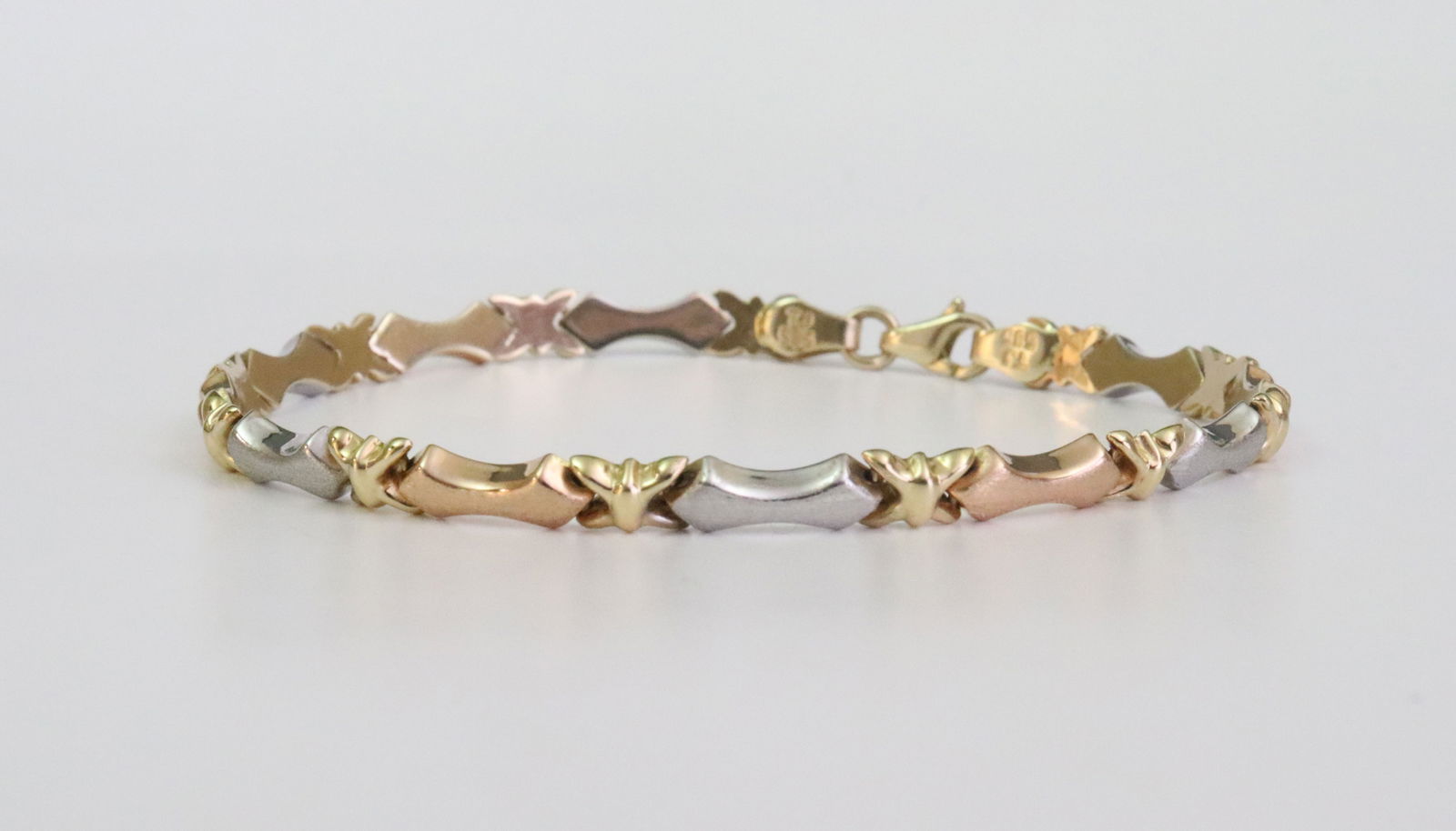 14K TRICOLOR LINK BRACELET: in white, yellow and rose brushed and polished gold, stamped '585 TJ', width 4.5mm, length 7.5in., 4.9gms., Opening Bid $200