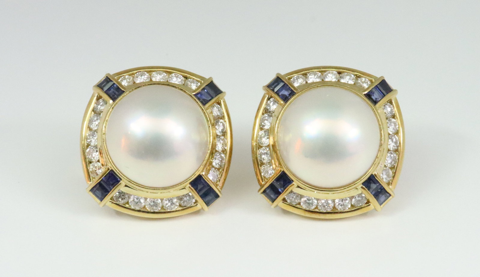 PAIR 18K MABE PEARL, DIAMOND & SAPPHIRE EARRINGS: each designed with a (13mm) mabe pearl within a bombe surround of 20 channel-set diamonds and 8 (2mm) caliber cut sapphires, total diamond weight for the pair approx. 1.60ctw (in our opinion: E-F