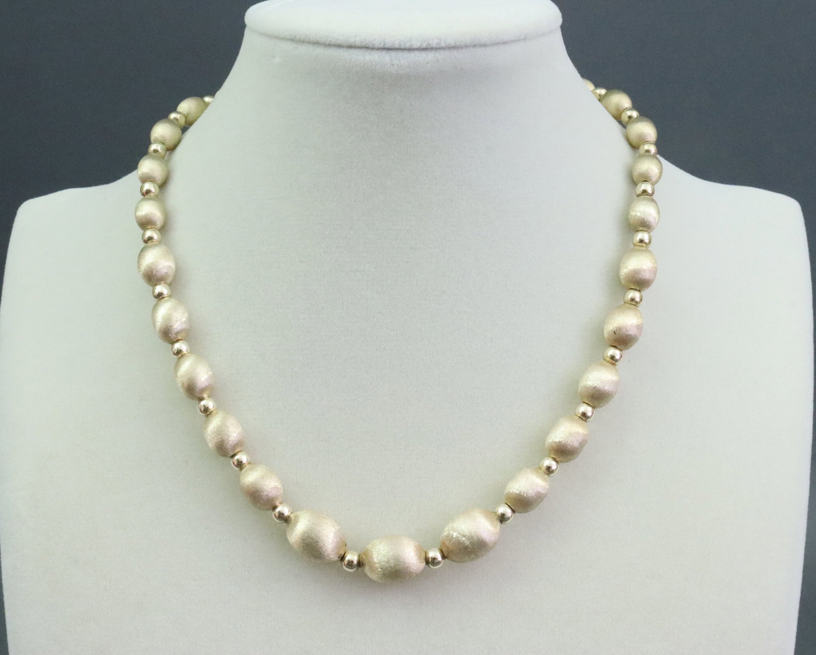 14K BRUSHED GOLD BEAD CHAIN NECKLACE: comprising (7-10mm) graduated oval beads strung on chain with (4mm) round bead spacers, in yellow brushed gold, stamped 14K, 16in., 17gms., Opening Bid $900