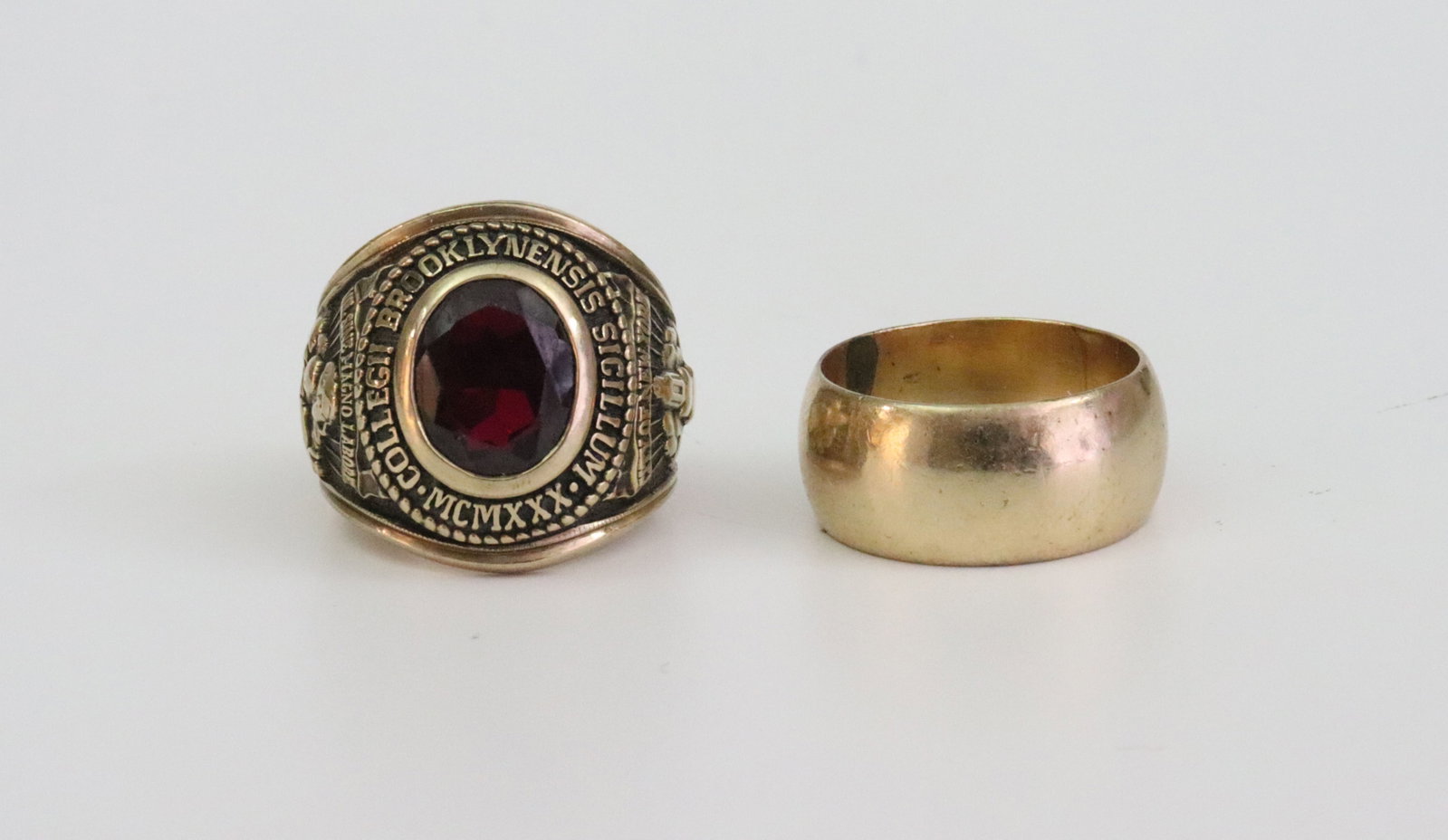 (2) GOLD RINGS: including a 14K wide band wedding ring (gold scuffs and dings), size 7 (moderate sizing line), 7.9gms., and a 10K 1964 Brooklyn College school ring with ruby stone (a couple minor stone dings), size 7