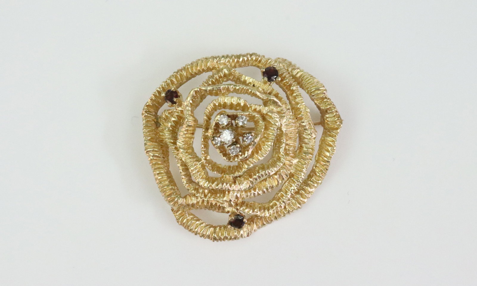 14K DIAMOND & GARNET FLOWER PIN: in openwork abstract design, set with 6 round natural diamonds approx. 0.20ctw, accented with 3 round garnets, in carved yellow gold, stamped 14K, 1.4in., 13.5gms., Opening Bid $600
