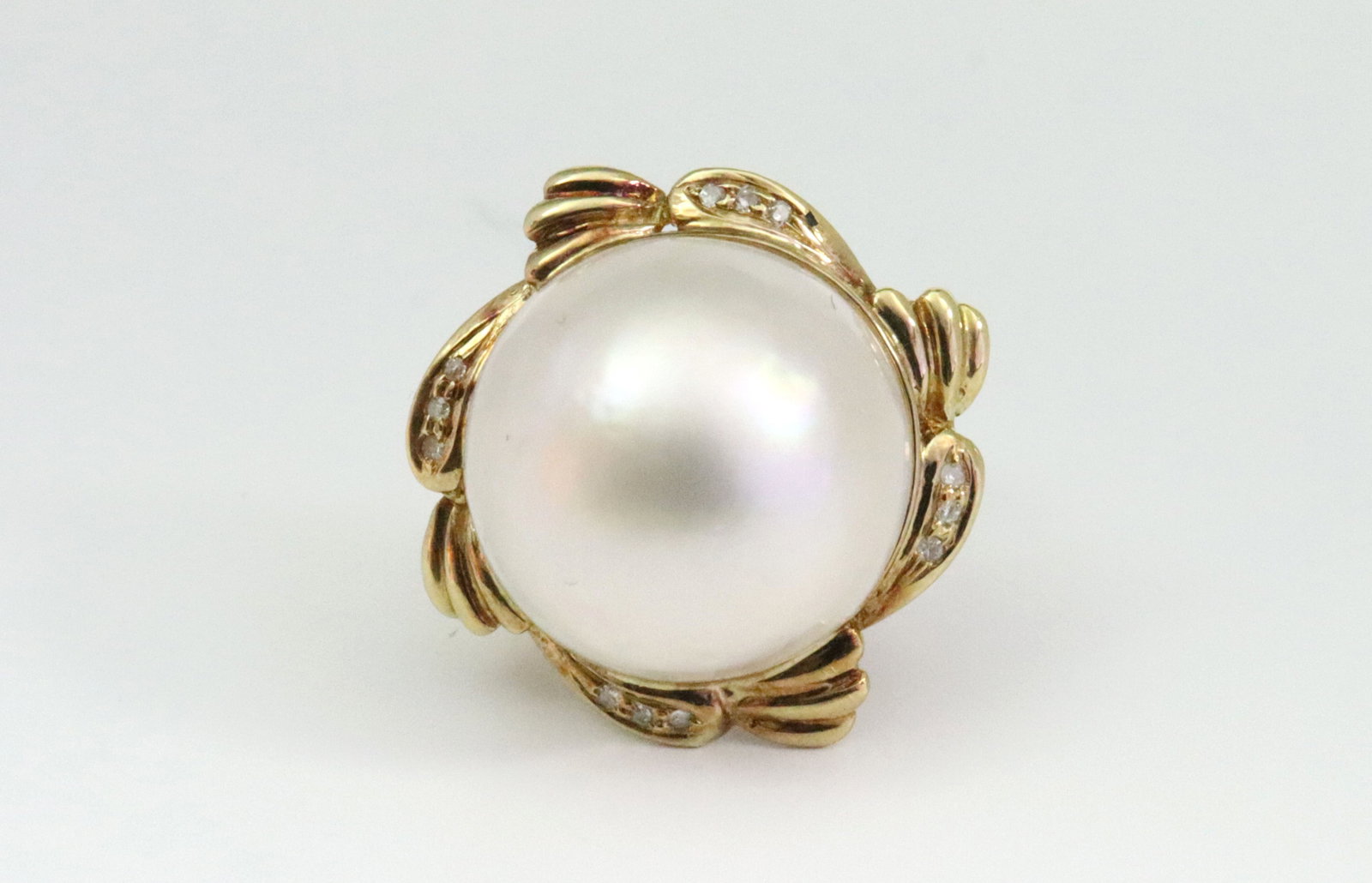 18K MABE PEARL & DIAMOND RING: designed with a 17mm mabe pearl centering a halo of gold set with 12 natural diamond melee, overall ring head 21mm, in yellow gold, stamped '18K 750', size 4, 7.9gms., Opening Bid $600