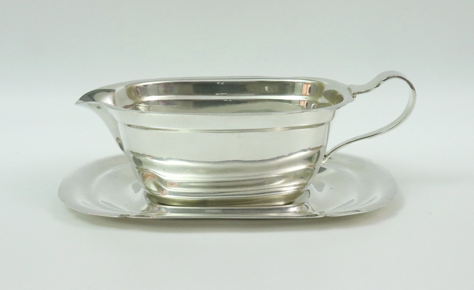 REED & BARTON STERLING GRAVY BOAT & UNDERPLATE: in Mayflower pattern, retailer stamped JE Caldwell & Co. #X550, and with 1939 & 1941 date marks, 2 shallow body dents, tray 7.25x5.5in., gravy boat height 2.25in., 9.9ozt., Opening Bid $400