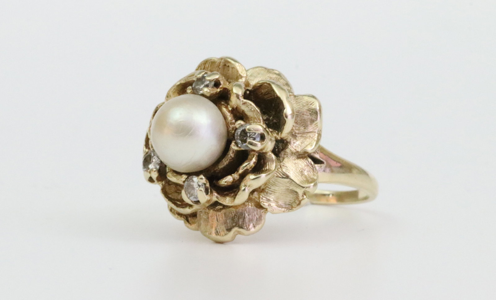 14K PEARL & DIAMOND FLOWER FORM RING: set with a 7.25mm cultured pearl, and 4 natural round diamonds approx. 0.16ctw, in textured yellow gold, tests 14K, size 6, gross weight 8.1gms., Opening Bid $300