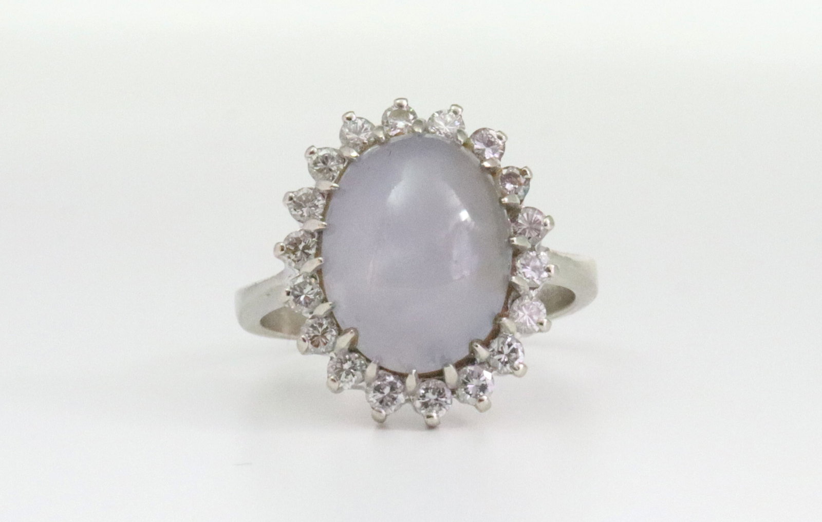14K STAR SAPPHIRE & DIAMOND HALO RING: set with an oval star sapphire cabochon approx. 12.00ct, within a surround of 18 round natural diamonds approx. 0.72ctw, in white gold, stamped '14K 10378', size 7.5, 6.4gms., Opening Bid $300