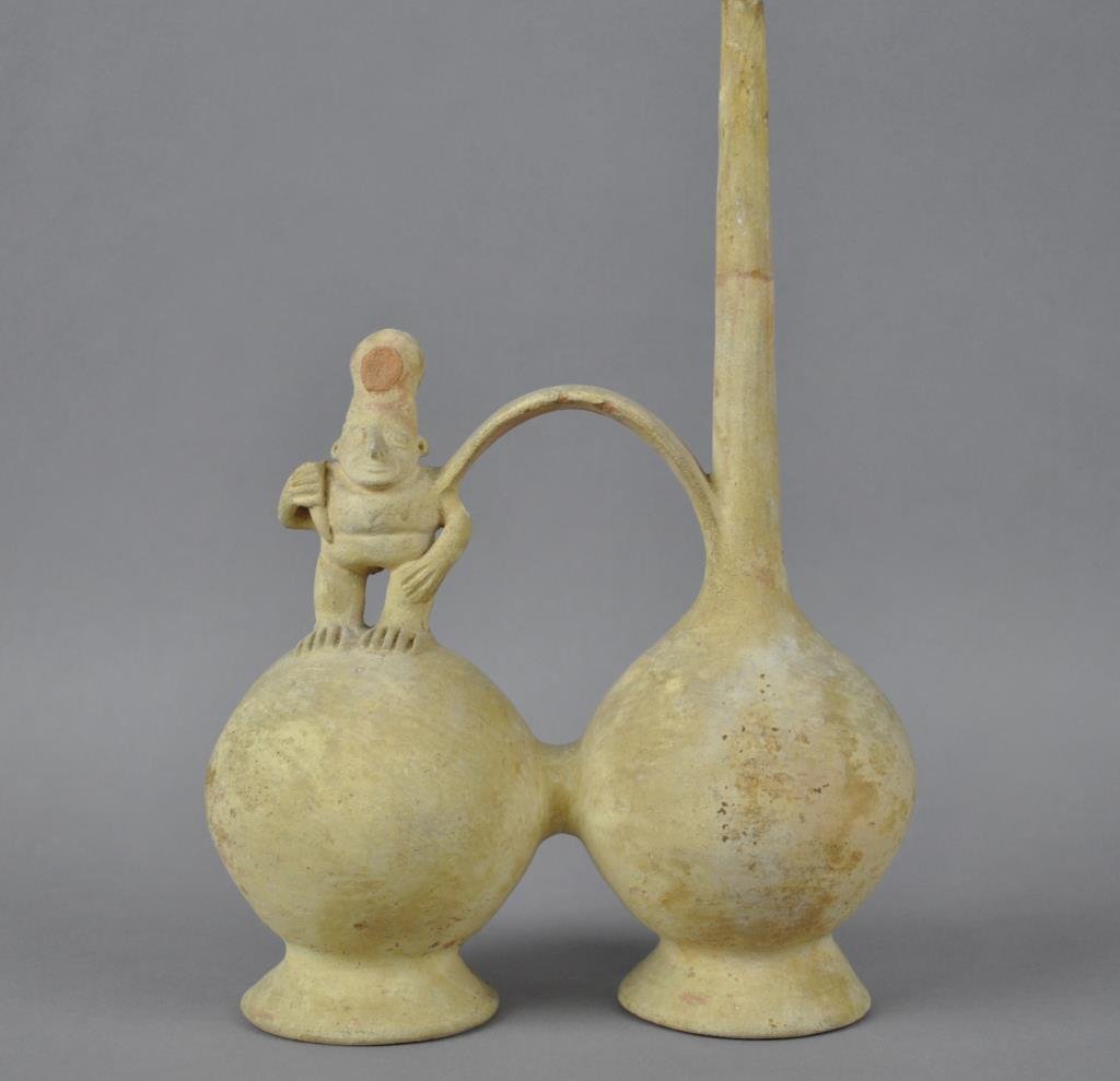 PRE-COLUMBIAN DOUBLE CHAMBER WHISTLING VESSEL: likely Peru, having two round chambers with a whistle spout on one, a standing figure on the other, whistle in rear of figure's hat (whistle spout with chips and possibly an old repair), 12x8in.