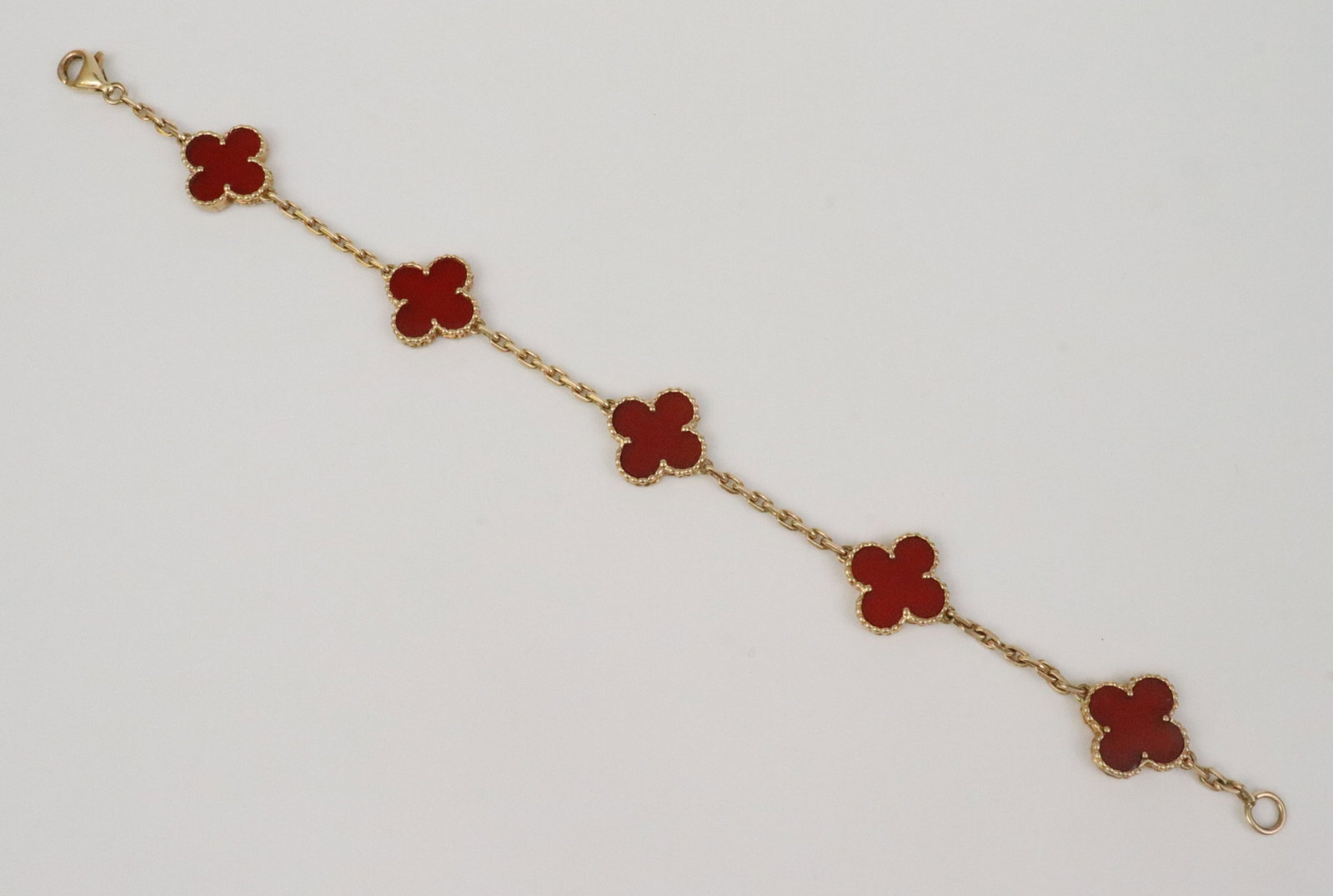 VAN CLEEF & ARPELS 5-MOTIF ALHAMBRA BRACELET: adorned with 5 carnelian quatrefoil motifs on cable chain, in 18K yellow gold, reference VCABL146553 / 750, stamped on first clover adjacent to clasp, clasp stamped 750, 7.75in., 10.6gms., accompanied
