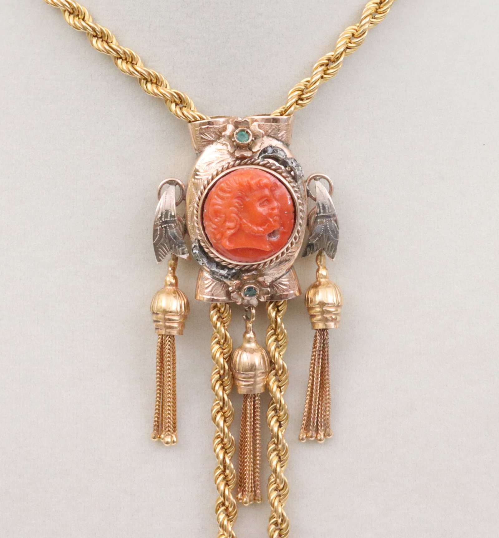 14K REPURPOSED VICTORIAN SLIDE ON 51" ROPE CHAIN: the slide set with a coral profile centerpiece (somewhat ill-fitting to frame, small puncture at chin, face line likely intrinsic), accented with 2 round emerald stones, and 8 rose cut diamonds
