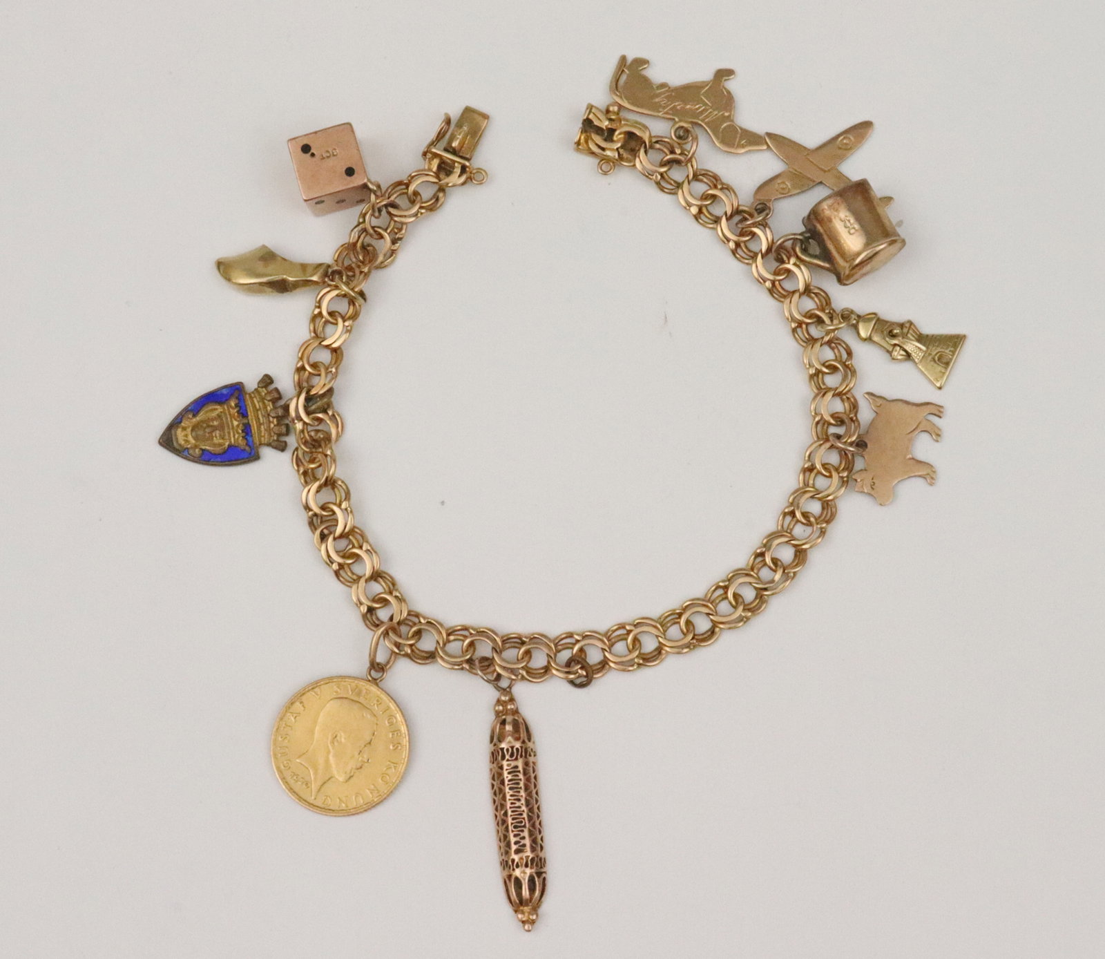18K SWEDISH CHARM BRACELET WITH (9) GOLD CHARMS: charms include a 21.6K (900 fine) 1920 Swedish 5 Kronor gold coin, an18K dachshund charm, 14K charms include a windmill (missing one rotor), a mezuzah, and a Dutch shoe (dent), 9K charms include a