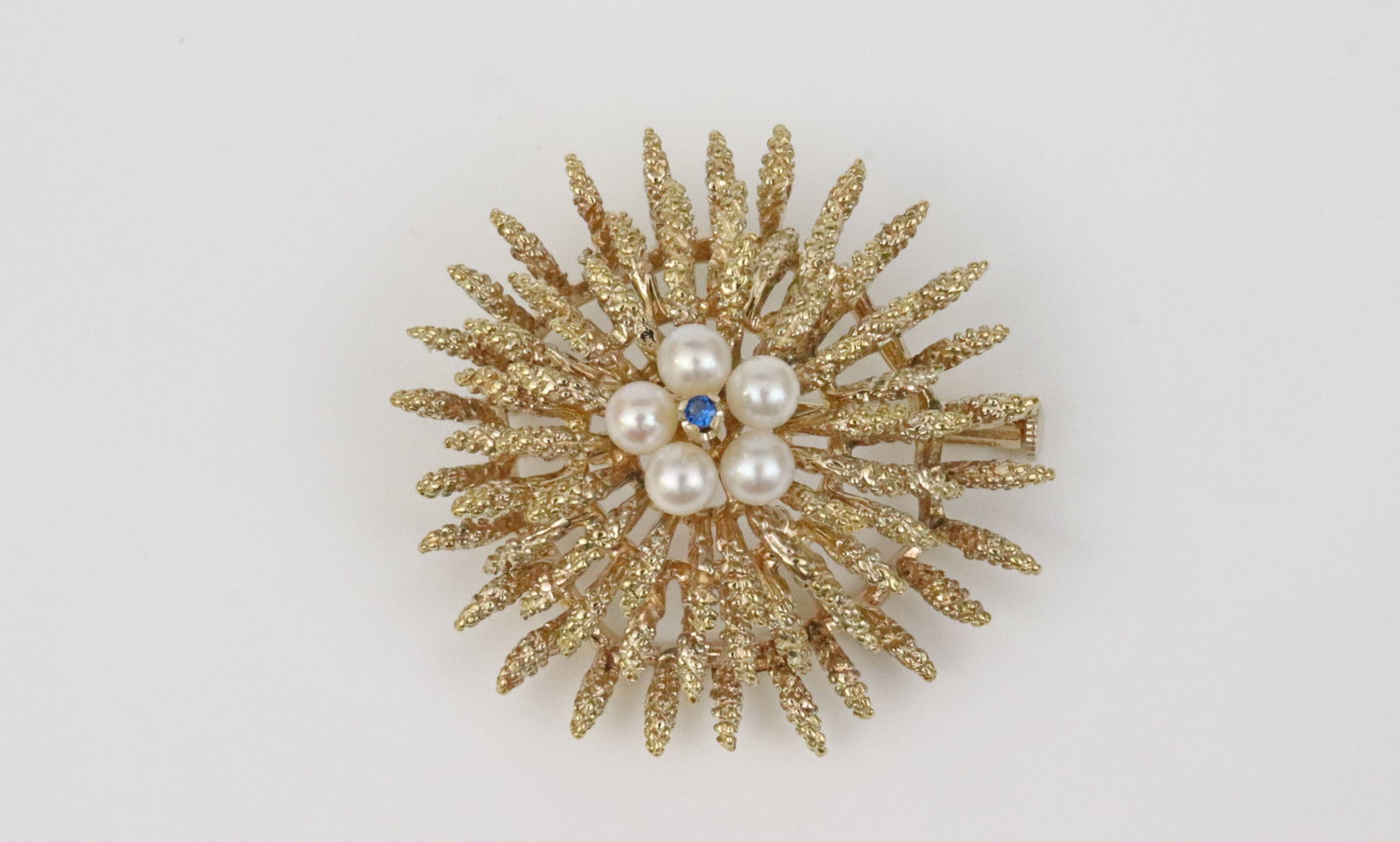 ITALIAN 18K PEARL & SAPPHIRE FLORAL BROOCH: set with 5 (4mm) cultured pearls centering a (2pt) sapphire, in yellow textured gold, stamped 'Italy 18K', 1.4in., 16.2gms., Opening Bid $700