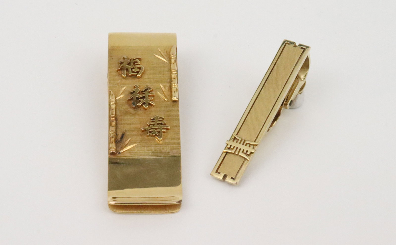 MANNING 14K MONEY CLIP & TIE CLIP: the money clip in embossed bamboo motif with Fu, Lu and Shou good fortune symbols, 2in., the tie clip with Shou symbol, 1.5in., each in yellow textured and polished gold signed '14K Manning',