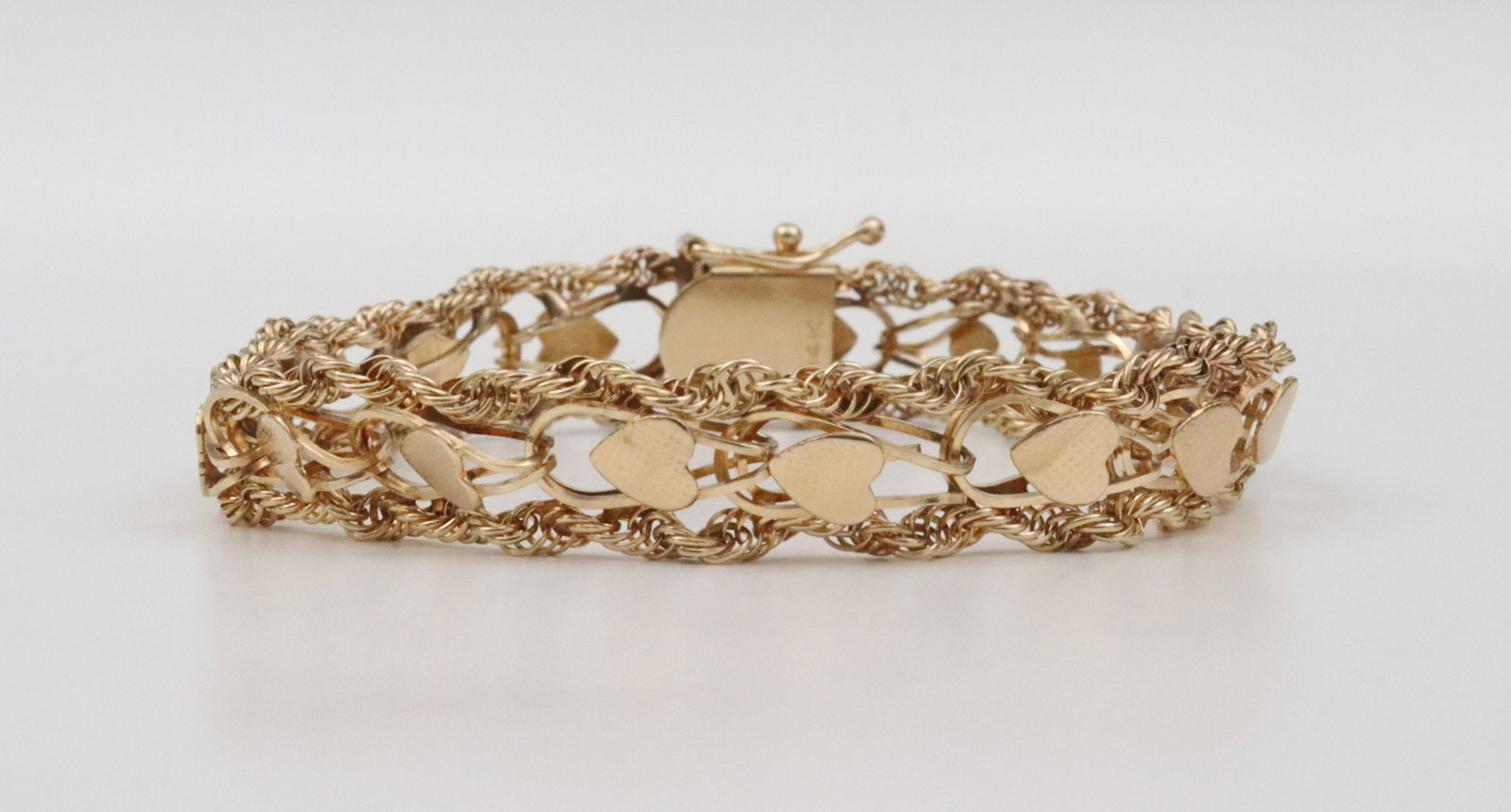 14K FANCY HEART LINK BRACELET: in heart link design with swirl rope trim, width 10.5mm, length 7.5in., in yellow gold, stamped 14K, safety chain and safety catch, 15.1gms., Opening Bid $600