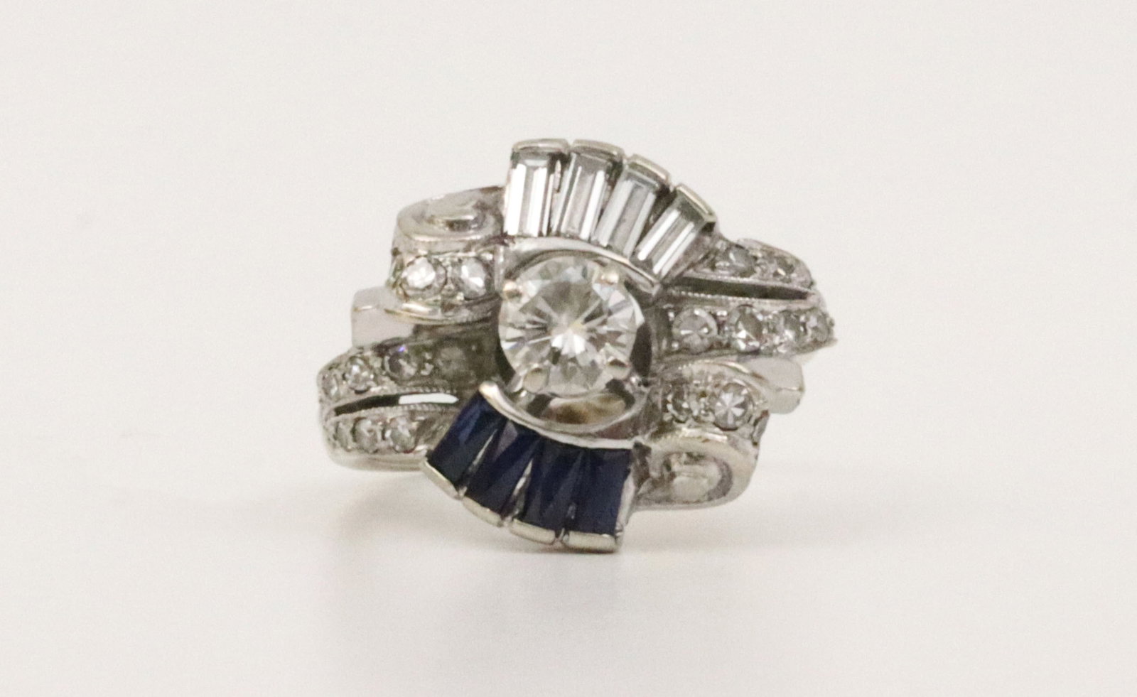 RETRO 14K DIAMOND & SAPPHIRE COCKTAIL RING: featuring 25 round and baguette diamonds approx. 1.15ctw, center diamond approx. 0.45ct (appear nice clean stones), accented with 4 sapphire baguettes approx. 0.36ctw, in white gold, tests 14K, size