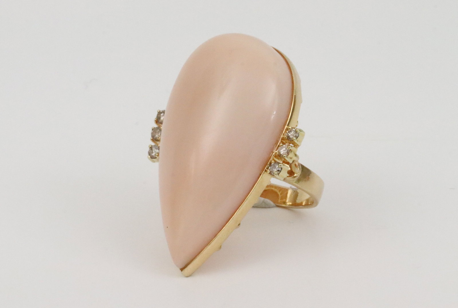 14K ANGEL SKIN CORAL & DIAMOND STATEMENT RING: featuring a large pear-cut coral cabochon approx. 41x22x12.8mm, flanked by 6 round natural diamonds approx. 0.30ctw, light scuffs mainly observed under magnification, minor nick to backside of stone, 