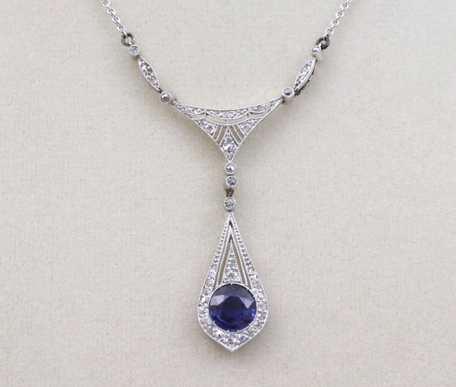 ART DECO SAPPHIRE & DIAMOND LAVALIER NECKLACE: the platinum lavalier portion bezel-set with a round sapphire approx. 1.70ct (7.5x4.2mm), accented with 49 melee diamonds, overall 2in., with replaced 9K cable chain and 14K clasp, all aptly tested,