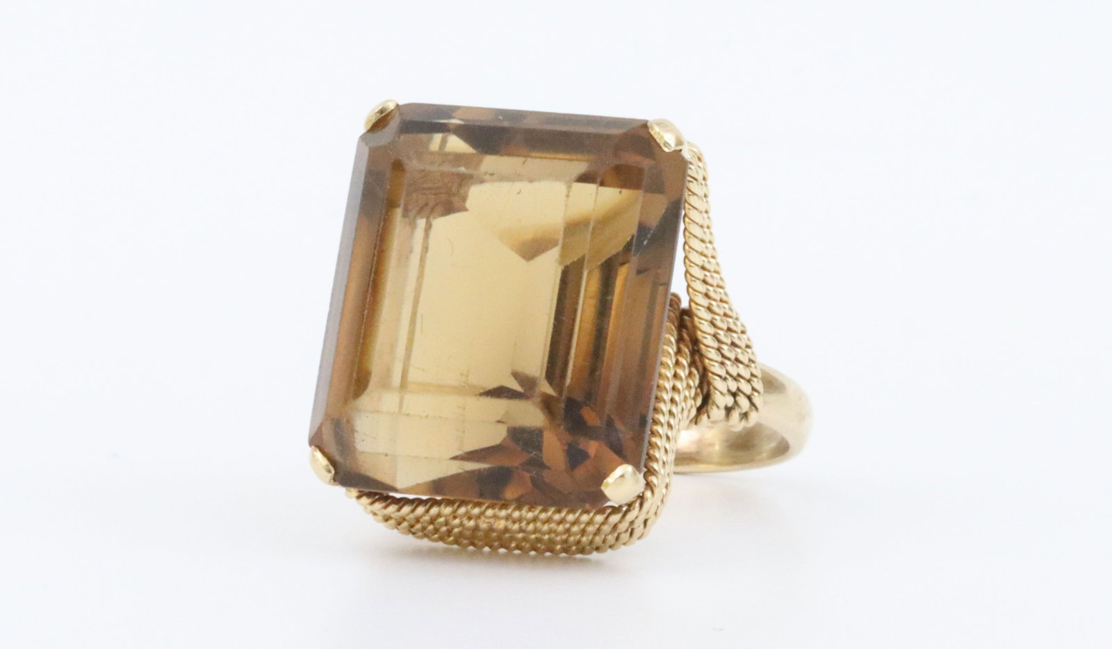 18K CITRINE COCKTAIL RING: featuring an emerald-cut citrine stone approx. 26.00ct, highlighted by a distinct wirework of woven rope trim, (stone facets with light scratches mainly observed under magnification), in yellow gold, 