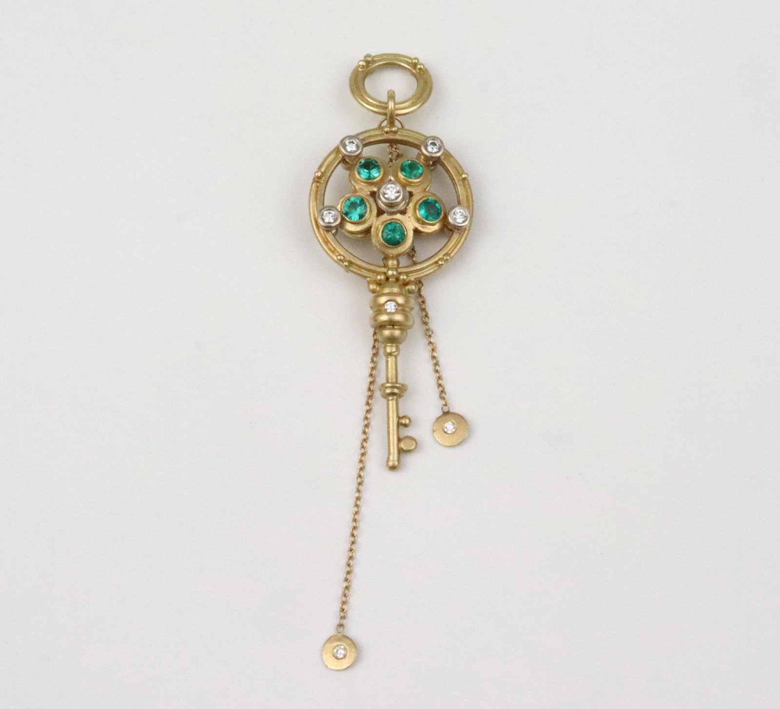 18K DIAMOND & GEMSTONE REVERSIBLE KEY PENDANT: double-sided gem-set heraldic style key pendant with large matching bale and double dangling chains, featuring 16 round natural diamonds approx. 0.30ctw, 5 green gemstones and a topaz approx.