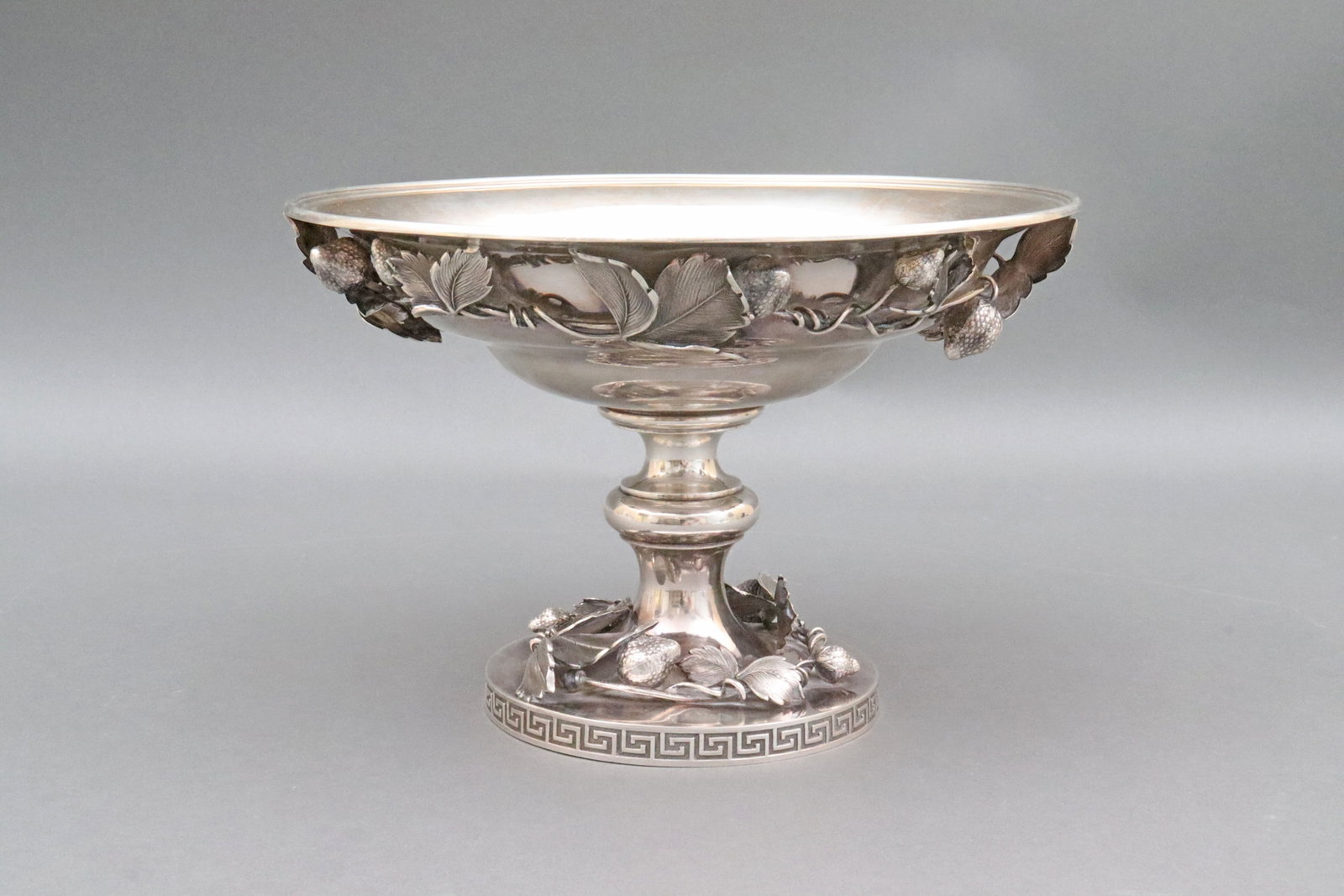 MOORE FOR TIFFANY STERLING STRAWBERRY COMPOTE: c.1857, the curved wide bowl decorated to its underside in winding leaf and strawberry design, the center knopped shaft set above a footed base having a Greek key design, the foot itself also cast in