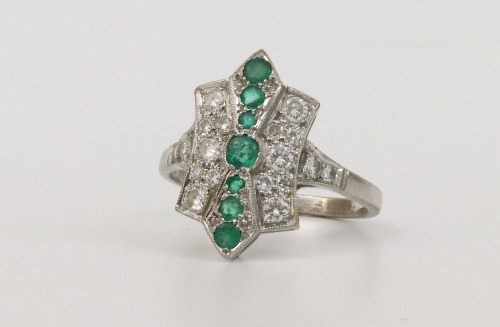 BRITISH 18K ART DECO EMERALD & DIAMOND RING: designed in shield form featuring 7 round emeralds approx. 0.30ctw, and 18 round natural diamonds approx. 0.47ctw, overall ring head 19x11mm, in white gold, hallmarks for London, 750, 1922 and maker