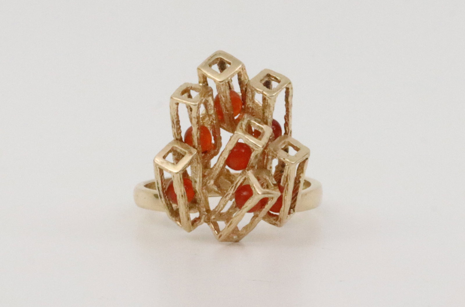 14K BRUTALIST ARCHITECTURAL RING: set with 7 carnelian-color 3mm beads, most are articulated within their openwork pillars, in yellow gold, stamped 14K, size 7, 5.3gms, Opening Bid $300