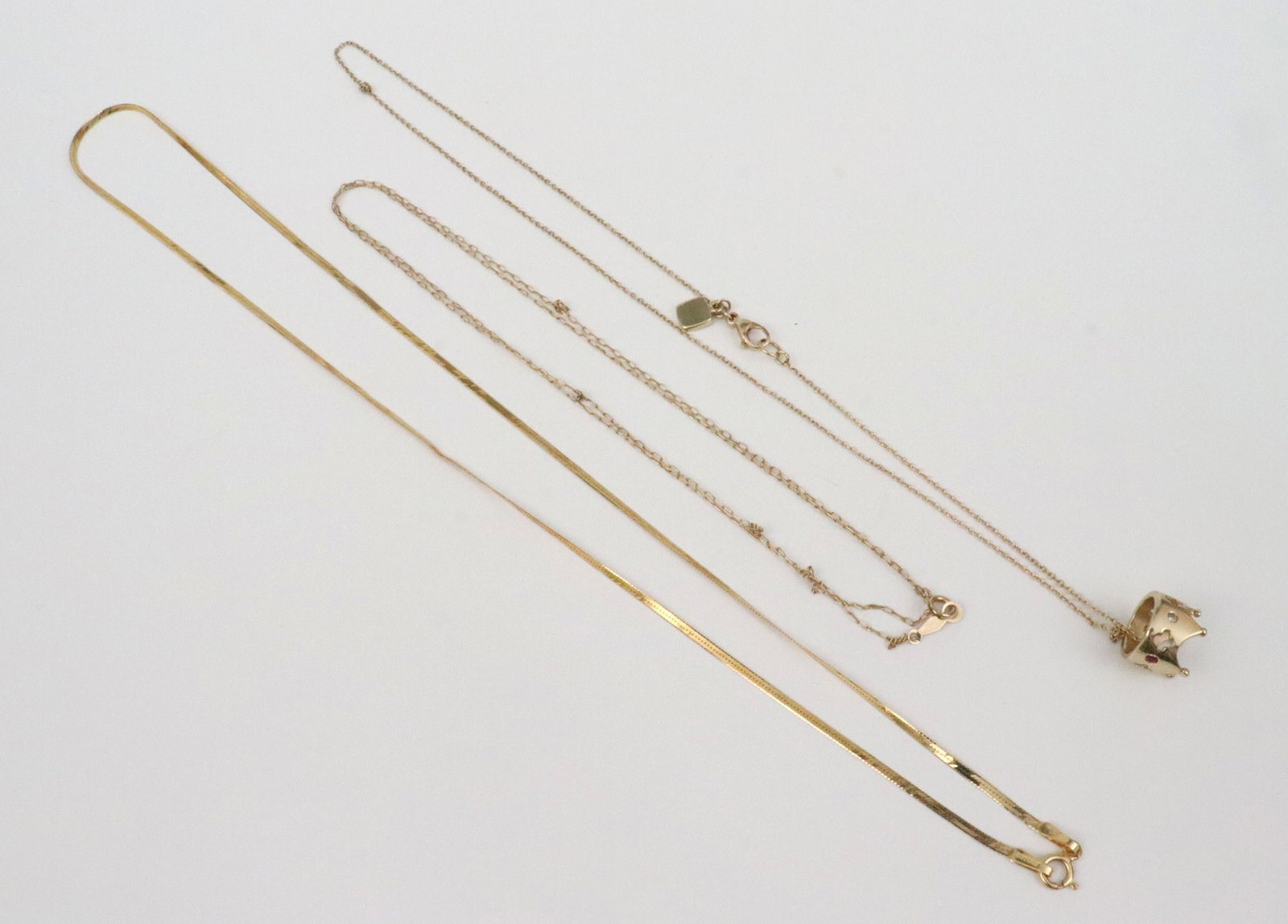 (3) AS-IS NECKCHAINS: including a 22" oval cable chain (a few knots), an 18" herringbone chain (dents), and a 15" cable chain with crown pendant set with 4 melee gemstones (does not come off chain, chain with knots), all