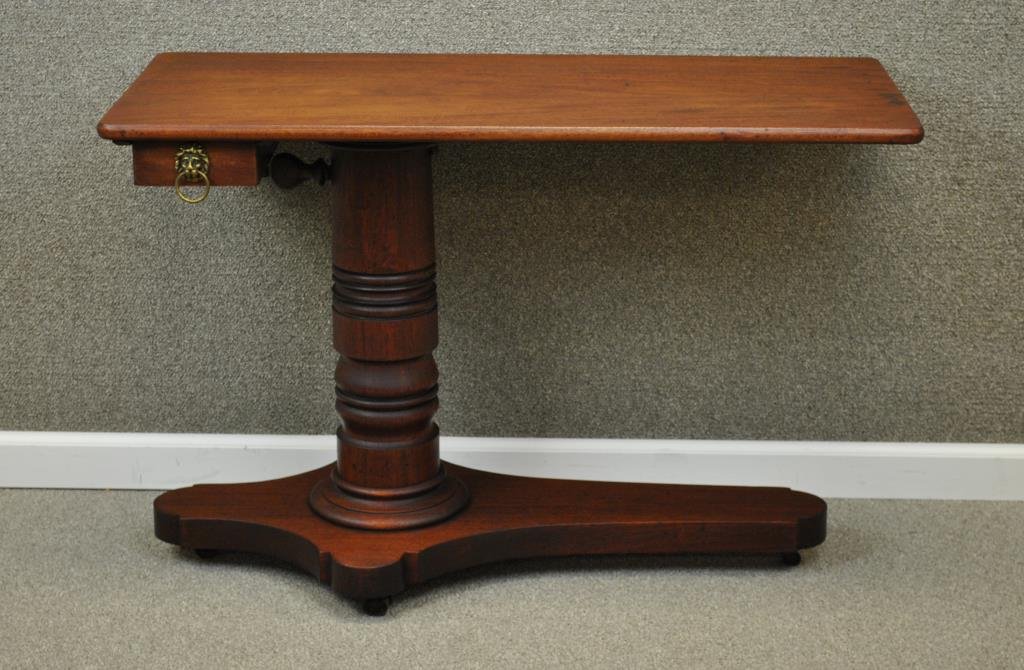 EDWARDIAN INVALID TABLE: likely mahogany, single drawer with lion ring pull, metal wheels, length 39in., width 18in., height adjustable