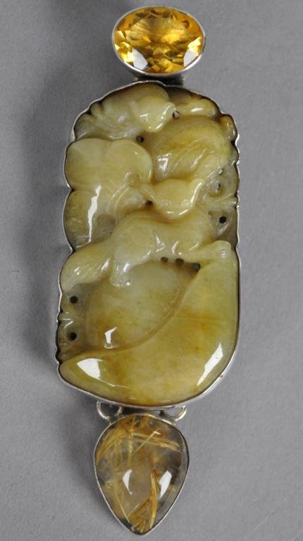AMY KAHN RUSSELL LARGE JADE BOUTIQUE BROOCH: the center panel comprising two-sided jade carving depicting cats, surmounted by a topaz stone, mounted in silver, with bale to be worn also as a pendant, stamped AKR Sterling, 3.75in.
